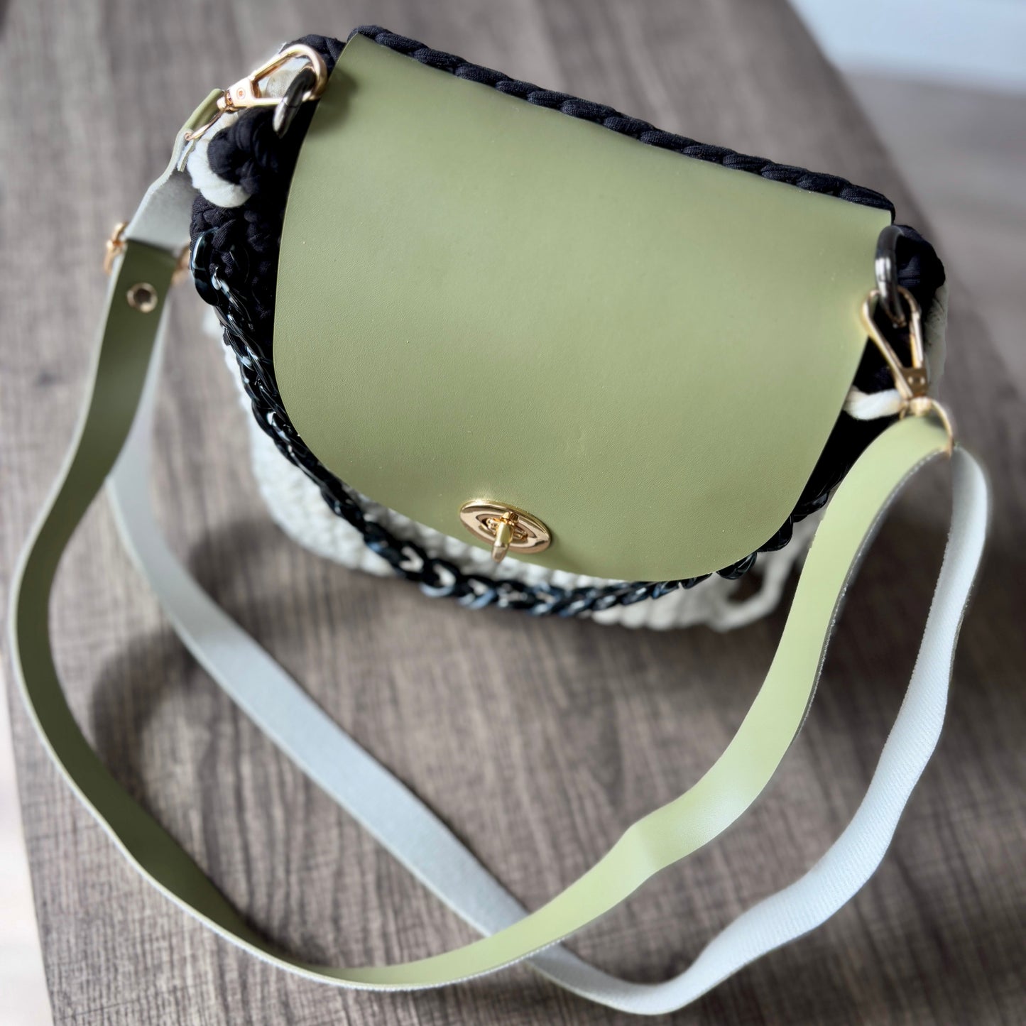Green handbag with a textured white base and black chain detail